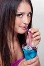 Young woman drinking blue cocktail