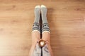 Young woman drinking cappuccino coffee and sitting on the wooden floor. Close up of female hands holding cup of coffee, sitting on Royalty Free Stock Photo