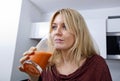 Young woman drinking carrot juice in kitchen Royalty Free Stock Photo