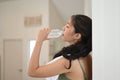 Young woman drinking clean water from bottle in living room. Royalty Free Stock Photo