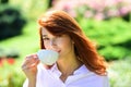 Young woman drinking coffe in spring pakr. Beautiful woman holding a coffee cup in her hand. Royalty Free Stock Photo