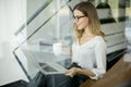 Young woman drinking coffe and working on laptop in office Royalty Free Stock Photo