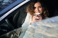 Young woman drinking coffee in car interior. Royalty Free Stock Photo