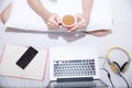 Young woman drinking coffee at home in her bed and checking her laptop, Royalty Free Stock Photo