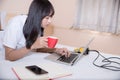 Young woman drinking coffee at home in her bed and checking her laptop, Royalty Free Stock Photo