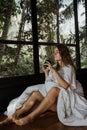 Young woman drinking coffee and enjoying morning in a tropical jungle bungalow