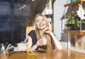 Young woman drinking coffee and reading book sitting indoor in urban cafe. Cafe city lifestyle. Casual portrait of teenager girl Royalty Free Stock Photo