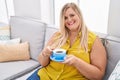 Young woman drinking coffee sitting on sofa at home Royalty Free Stock Photo