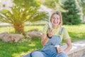 Young woman drinking coffee, sunbathing and laughing in the park during the covid pandemic. New normality, mask, way of life