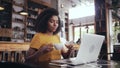 Young woman drinking coffee while using laptop in cafe