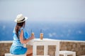 Young in outdoor cafe enjoying sea view. Beautiful woman relax during exotic vacation on the beach enjoying frappe Royalty Free Stock Photo