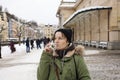 Young woman drinking from cup with therapeutic mineral water at a natural hot spring in Karlovy Vary during winter time