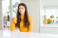 Young woman drinking a glass of fresh orange juice with a confident expression on smart face thinking serious Royalty Free Stock Photo