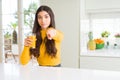 Young woman drinking a glass of fresh orange juice pointing with finger to the camera and to you, hand sign, positive and Royalty Free Stock Photo