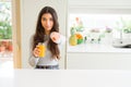 Young woman drinking a glass of fresh orange juice pointing with finger to the camera and to you, hand sign, positive and Royalty Free Stock Photo