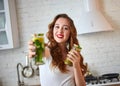 Young woman drinking green smoothie and fresh water with cucumber, lemon, leaves of mint on the kitchen table with fruits and Royalty Free Stock Photo