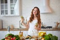 Young woman drinking green smoothie and fresh water with cucumber, lemon, leaves of mint on the kitchen table with fruits and Royalty Free Stock Photo