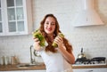 Young woman drinking green smoothie and fresh water with cucumber, lemon, leaves of mint on the kitchen table with fruits and Royalty Free Stock Photo