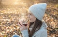 Young woman is drinking hot tea in an autumn Park in the light of the sunset. Cozy lifestyle in the autumn cold season Royalty Free Stock Photo