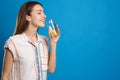 Young woman drinking lemon water on blue background. Space for text Royalty Free Stock Photo