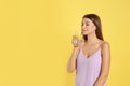 Young woman drinking lemon water on yellow. Space for text Royalty Free Stock Photo