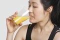 Young woman drinking orange juice over gray background Royalty Free Stock Photo