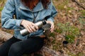 Young woman drinking tea in cup. Woman pours a drink into a mug from a thermos. Girl drinking tea while hike Royalty Free Stock Photo