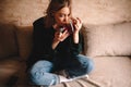 Young woman drinking tea and eating chocolate while sitting on sofa at home Royalty Free Stock Photo