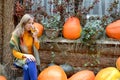 Young woman drinking tea among orange pumpkins in the yard of a rural house