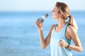 Young woman drinking water from bottle after fitness exercises on beach Royalty Free Stock Photo