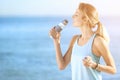 Young woman drinking water from bottle after fitness exercises on beach Royalty Free Stock Photo