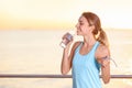 Young woman drinking water from bottle after fitness exercises on pier Royalty Free Stock Photo