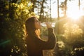 Young woman drinking water from bottle in nature.Bottled water.Hydration.Water intake for healthy body and skin.Natural mineral