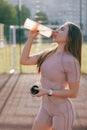 Young woman drinking water from bottle after training on the sports ground Royalty Free Stock Photo