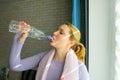 Young woman drinking water after exercise. Smiling attractive fitness girl with towel after training. Sport at home during Royalty Free Stock Photo