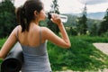 Young woman drinking water after training at sunny mountain hill. Outdoor workout. Healthy lifestyle Royalty Free Stock Photo