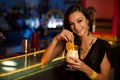 Young woman drinks a cocktail in night club