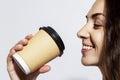 A young woman drinks coffee from a craft glass. Beautiful smiling brunette in the sunny morning light. Close-up. White background Royalty Free Stock Photo