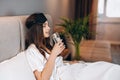 young woman drinks water in the bed. model with brown hair with a glass of water in the bed in the bedroom. drink a Royalty Free Stock Photo