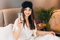 young woman drinks water in the bed. model with brown hair with a glass of water in the bed in the bedroom. drink a Royalty Free Stock Photo