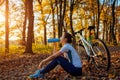 Young woman drinks water after workout on bike. Healthy lifestyle. Riding bicycle in autumn forest Royalty Free Stock Photo