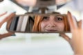 Young woman driver checking rear view mirror looking backwards while driving a car Royalty Free Stock Photo