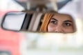 Young woman driver checking rear view mirror looking backwards while driving a car