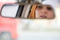 Young woman driver checking rear view mirror looking backwards while driving a car