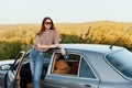 A young woman driver looks out of the car at the autumn landscape and smiles satisfactorily Royalty Free Stock Photo