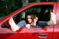 Young woman driver resting in a red car, put her feet on the car window and flirting, happy travel concept Royalty Free Stock Photo