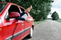 Young woman driver resting in a red car, put her feet on the car window, happy travel concept Royalty Free Stock Photo