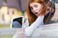 Young woman driving a car backwards. Girl with funny expression on her face while she made a fender bender damage to a rear Royalty Free Stock Photo