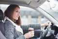 Young woman driving car in the city holding coffee Royalty Free Stock Photo