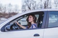 Young woman driving a car in the city. Portrait of a beautiful woman in a car, looking out of the window and smiling. Travel and